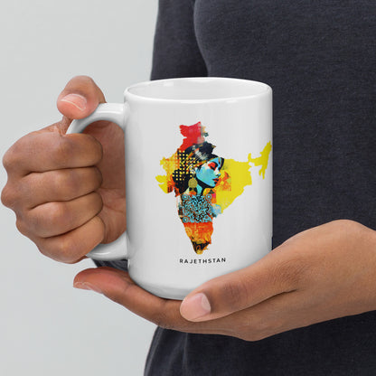 A 15 oz mug held by a woman, featuring a vibrant map of India in the style of fauvism and Bamileke art. The high-quality image captures robotic motifs and the artistic nuances of Prateep Kochabua, set against light gray and dark amber, embodying the fusion of fauvist figuratism and Afrofuturism